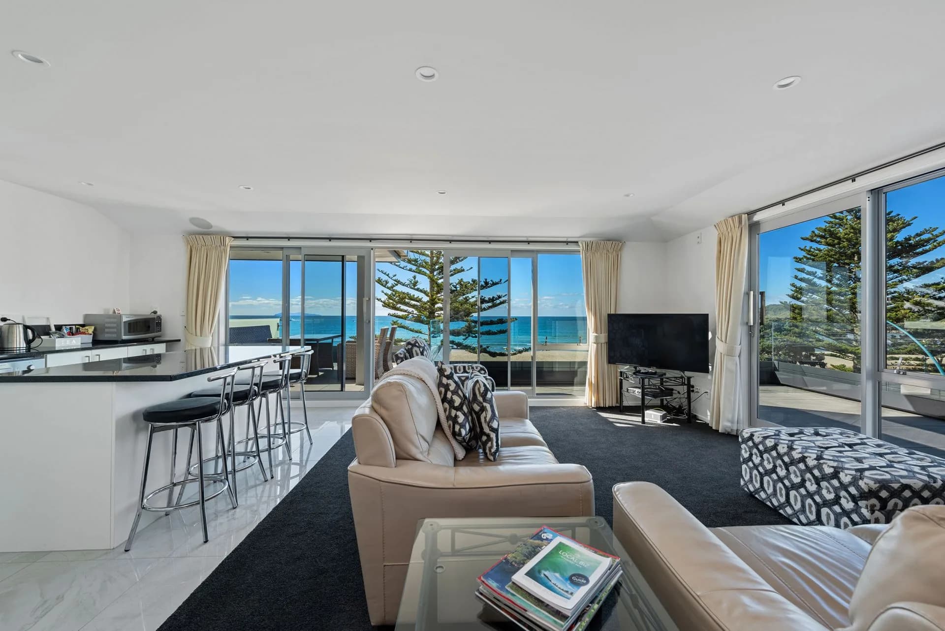 Living room with ocean views, leather sofas, and kitchen bar seating.