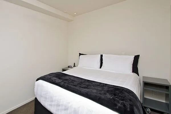 Bedroom with white and black bedding, flanked by two bedside tables.