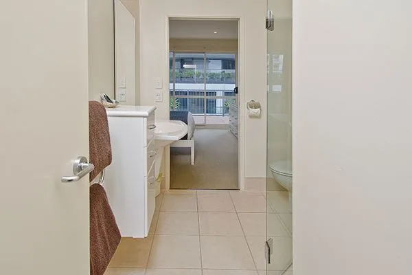 Bathroom with glass shower, vanity, and view into adjoining living area.