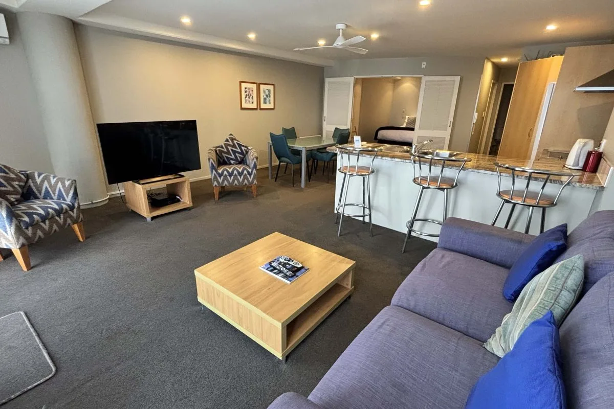 Living room with sectional sofa, armchairs, TV, and breakfast bar seating.
