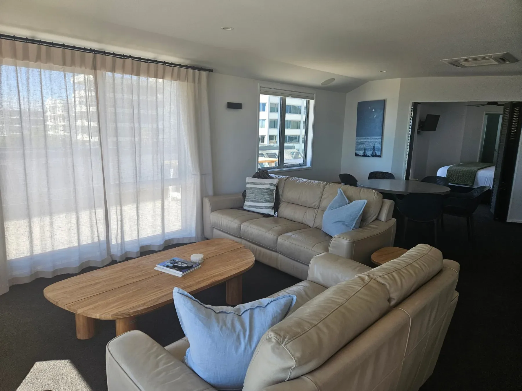 Living room with cream leather sofas, wooden coffee table and dining area.